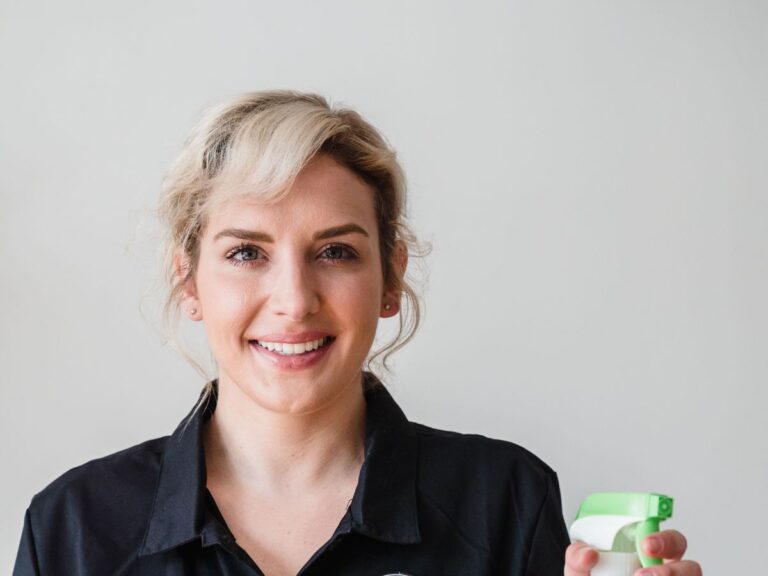 Smiling professional house cleaner holding a spray bottle